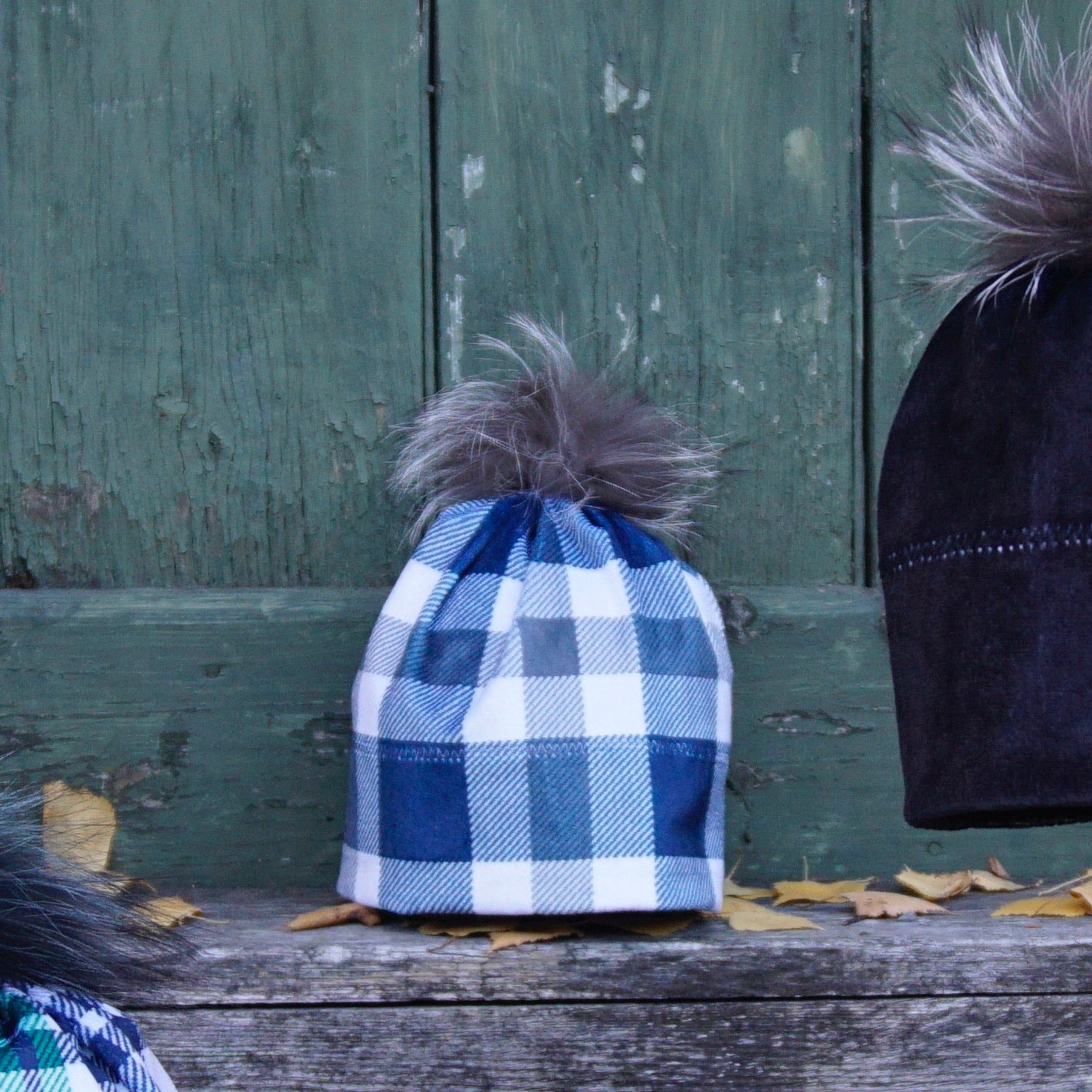 Bilde av rutete klassisk blå lue til dame og herre. Med pelsdusk sydd om av ekte pels.