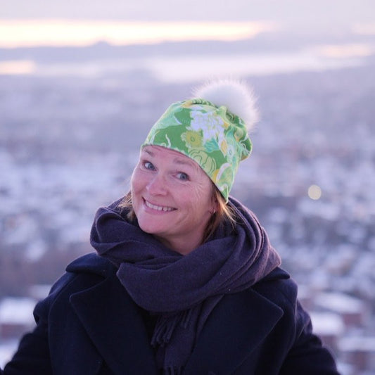 Bilde av dame med grønn lue med blomster og pelsdusk ved Holmenkollen i Oslo.